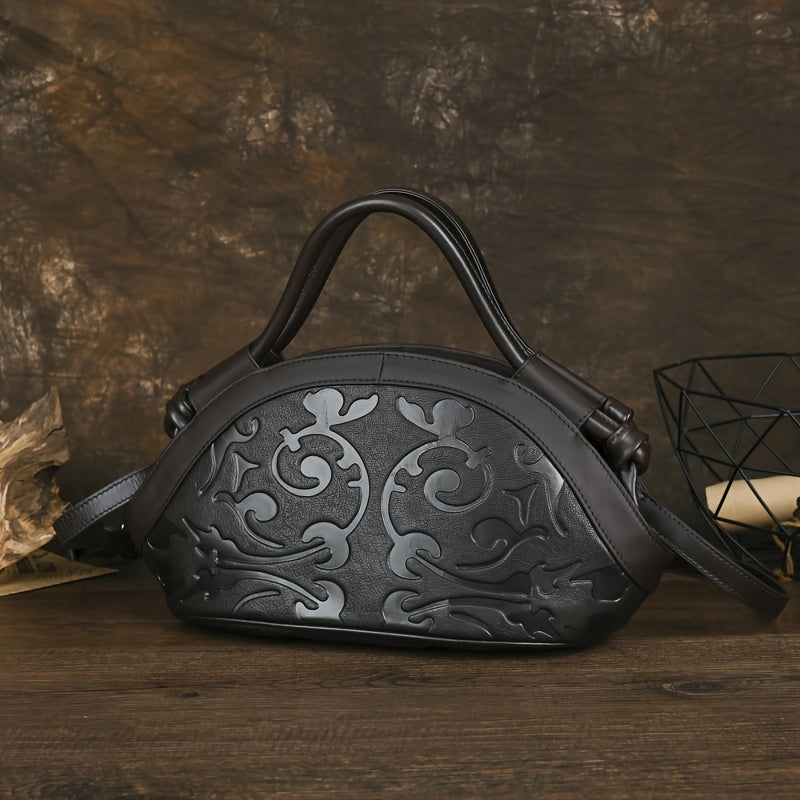 Black genuine leather handbag with embossed floral pattern and adjustable shoulder strap.