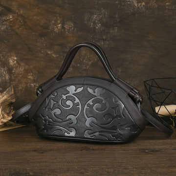 Sac à main en cuir véritable noir avec motif floral embossé et bandoulière réglable.