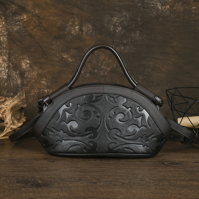 Black genuine leather handbag with embossed floral pattern and adjustable shoulder strap.